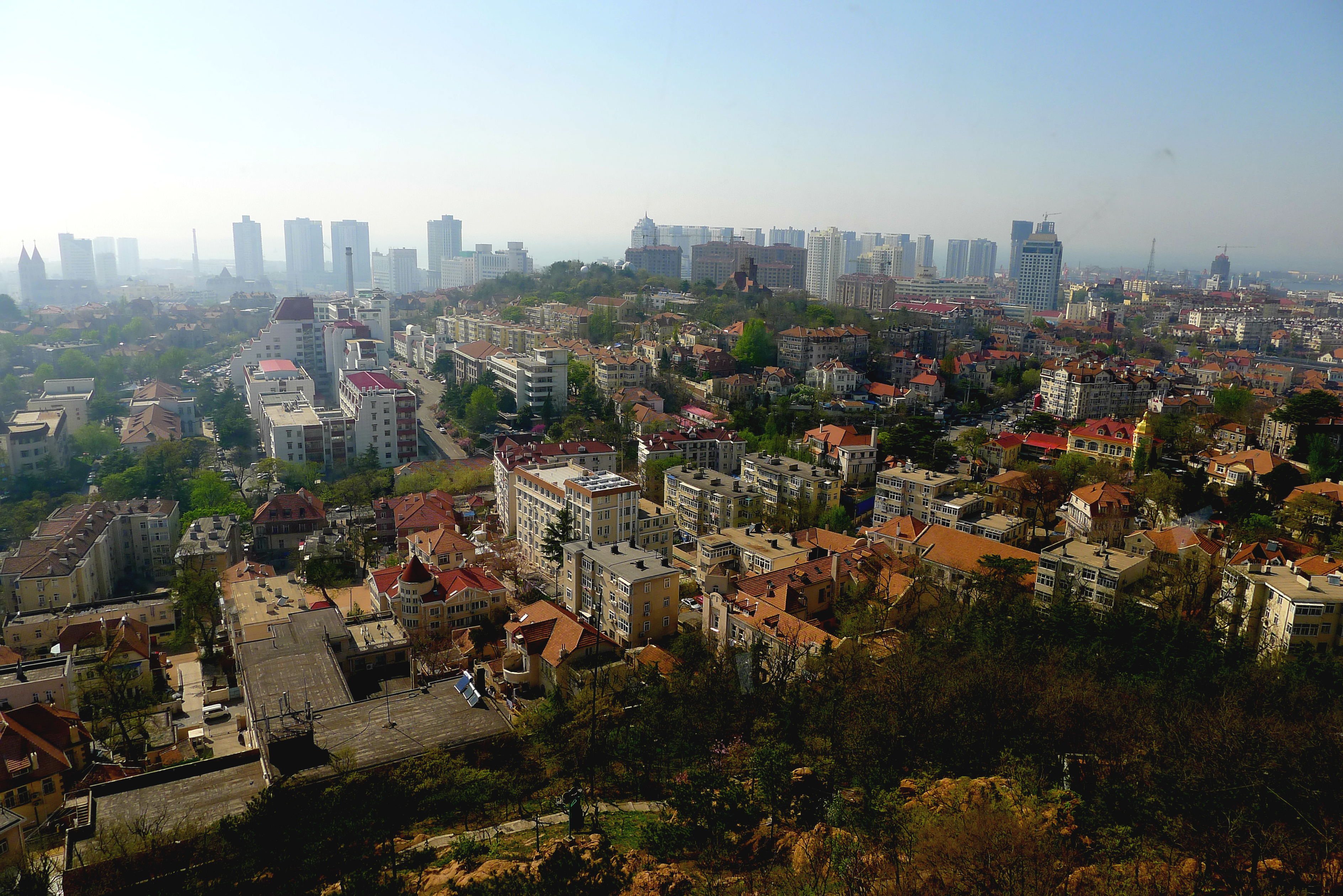 Qingdao red-tiled rooftops and modern skyline in daylight